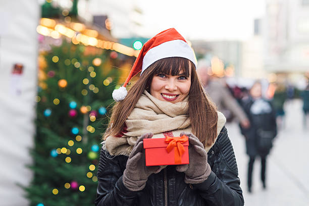 istock beautiful woman in santa hat holding present box 626488002