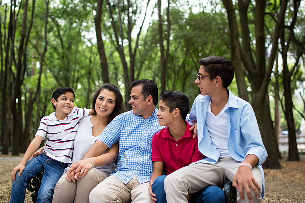 istock Affectionate latin family sitting on bench and looking at mother 626489046