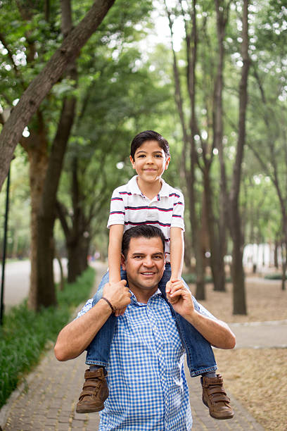 istock Latin father carrying boy on shoulders and smiling at camera 626489818