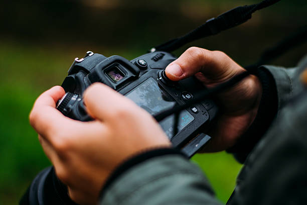 Young man holding camera A young man holding a DLSR camera in a natural environment. slr camera stock pictures, royalty-free photos & images