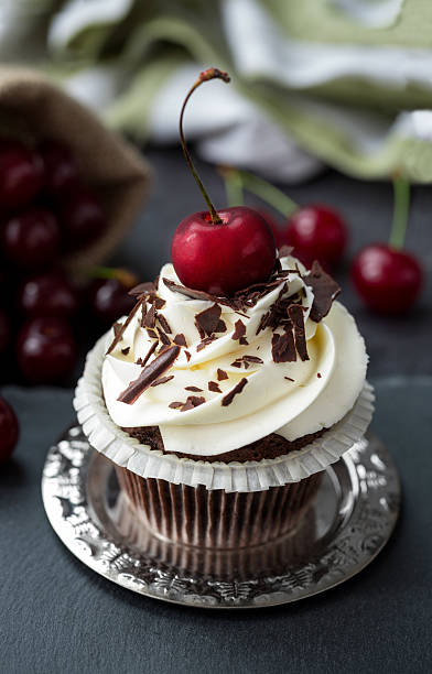 istock Chocolate cupcakes with cream and fresh cherry close up 626509344