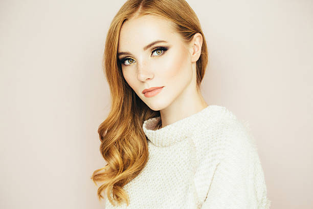 Back view of redhead woman with long ginger wavy hair on a white studio background