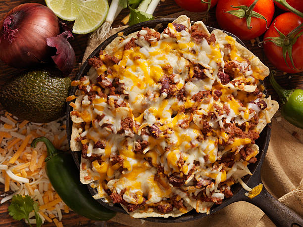 Chilli Cheese Skillet Nachos Chilli Cheese Skillet Nachos - Photographed on Hasselblad H3D2-39mb Camera nacho chip stock pictures, royalty-free photos & images