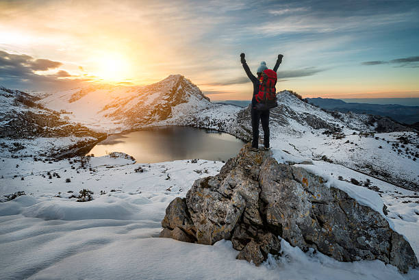 escursionista donna in aumento di braccia nel segno della vittoria sulla montagna innevata - snow hiking foto e immagini stock