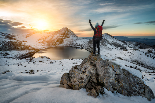 Hiker woman rising arms in victory sign on snowy mountain