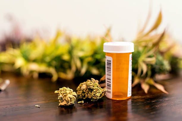 処方薬のボトルの隣に座っているマリファナの芽 - medical marijuana ストックフォトと画像