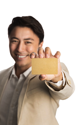 Attractive man in a bright beige suit, holding a golden VIP card smiling towards camera. White background.