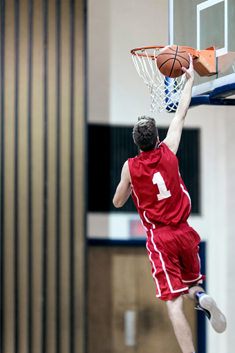Young male basketball player attempting a dunk