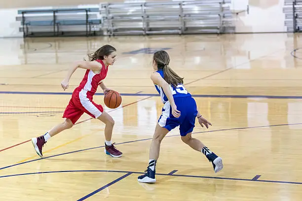 Teenage female basketball player one on one against another girl