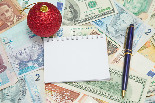 Blank notebook page with Christmas decoration and pen on background from world currencies