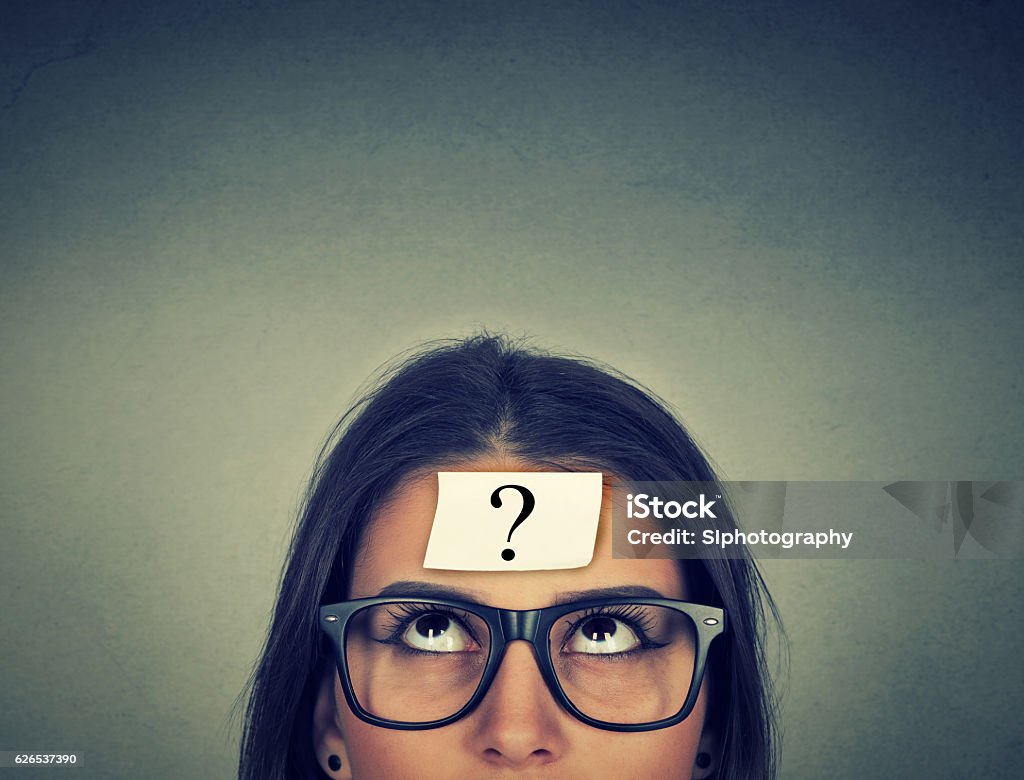 thinking woman with question mark thinking woman with question mark on gray wall background Contemplation Stock Photo