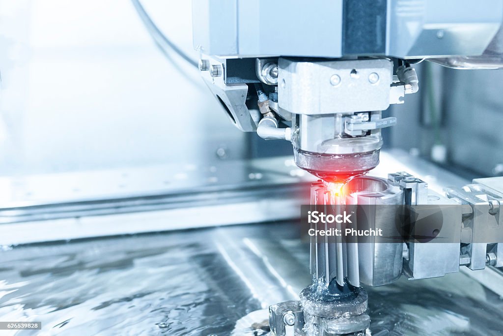 Close-up of the wire - EDM CNC machine Close-up of the wire - EDM CNC machine while cutting the sample work pieces in light blue tone and lighting effect Cultures Stock Photo