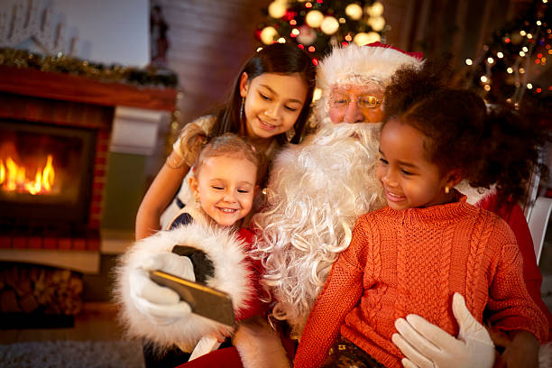 Santa Claus sharing smart phone with children Santa Claus sharing smart phone with children in Christmas atmosphere santa claus photos stock pictures, royalty-free photos & images