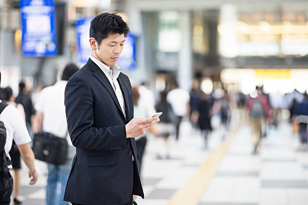 japanese businessman using mobile phone at the station - rush hour commuter on the phone tokyo prefecture imagens e fotografias de stock