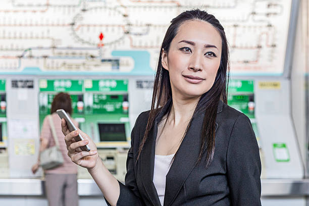 businesswoman waiting at station with mobile phone - rush hour commuter on the phone tokyo prefecture imagens e fotografias de stock