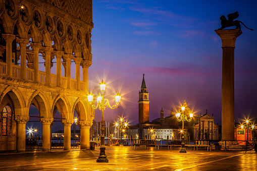 Twilight draws to a close as dawn approaches over St. Mark's Square in Venice, Italy.  To the left is the Doges Palace and in the background is the island of San Giorgio Maggiore.  To the right is a statue of a winged lion on a pillar - the symbol of Venice.
