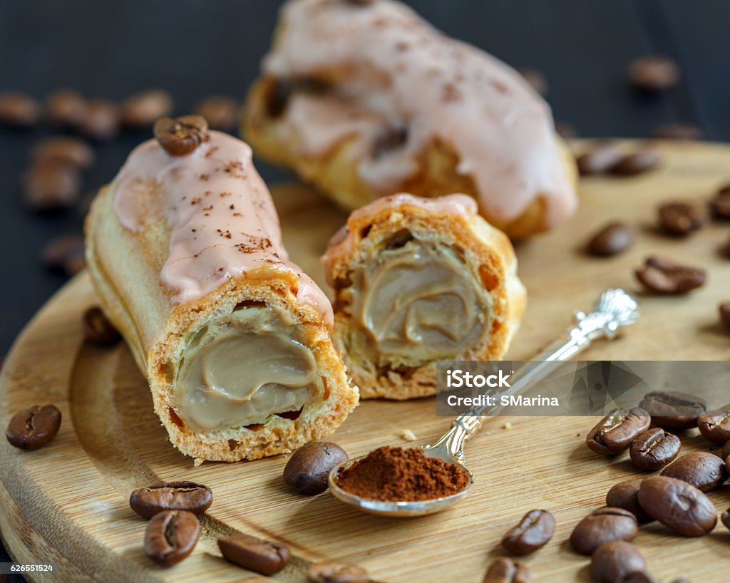 Delicious coffee eclairs. Eclairs with coffee custard on a wooden stand. Coffee Crop Stock Photo