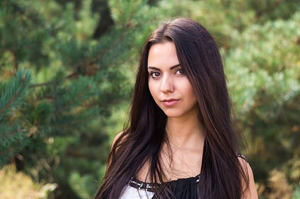 istock Graceful charming brunette model posing in black dress  coniferous park 626553656