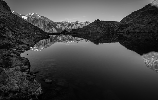 Sunrise on the calm waters of Lac de Louvie, the snow capped peaks of Petit Combin and Mont Blanc are visible in the background.