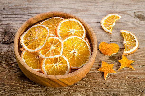 wooden bowl with dry orange on wooden table