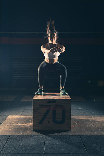 Strong woman jump on a crate in a gym stock photo