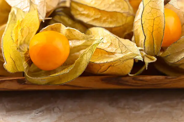 Physalis in a wooden dish on a brown table