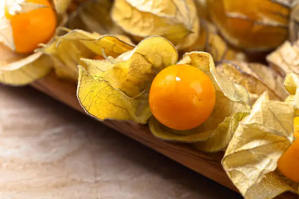 Physalis in a wooden dish on a brown table