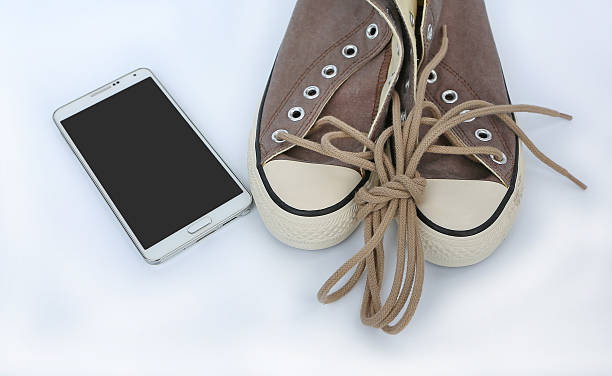 istock Pair of new sneakers with smart phone on white background 626587618