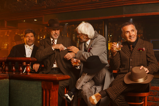 Best friends celebration. Retro Pub. Old fashioned, senior men  enjoying in pub, drinking alcohol, whiskey, martini.  Very shallow DOF .