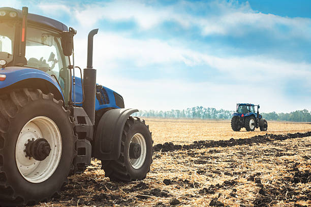 due trattori che lavorano in un campo. - plowed field dirt sowing field foto e immagini stock