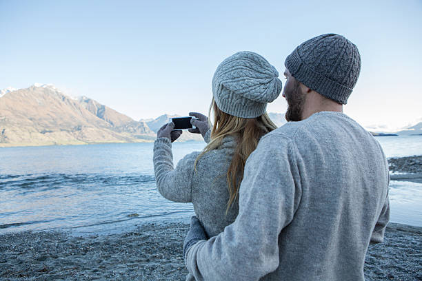 istock Young couple using smart phone to take selfie portrait 626590048