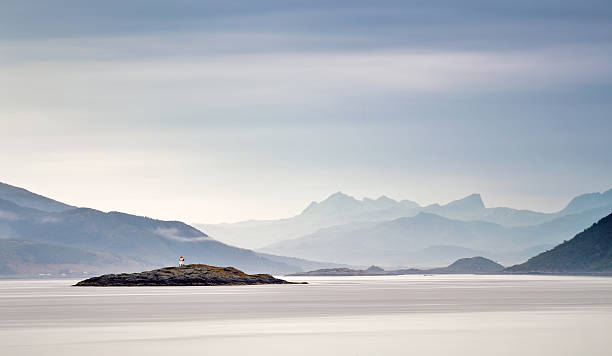Photo of Coast of Norway sea. Clouds of haze. Beacon on rock