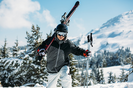 Man fully equipped for skiing climbing the hill