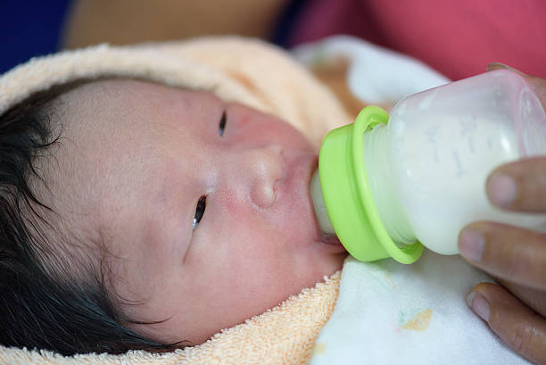Newborn drinking milk from bottle. stock photo