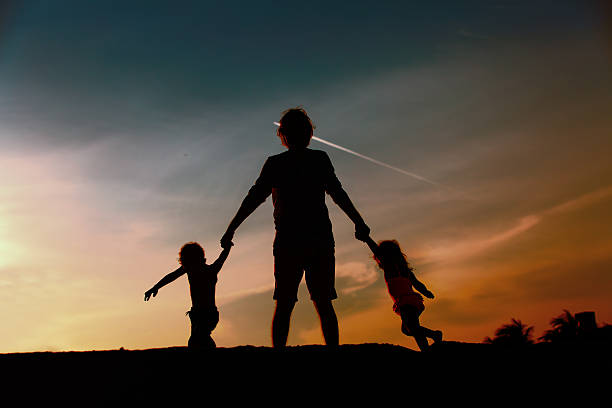 istock father with son and daughter silhouettes play at sunset 626612100