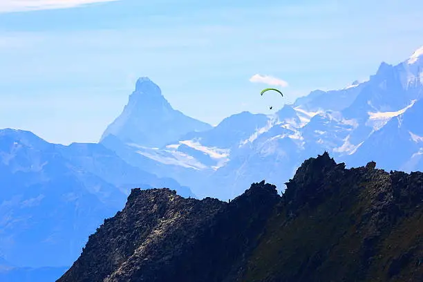 Far away freedom: Paragliding above Matterhorn and Weisshorn alpine massif, Swiss Alps, Switzerland – view from eggishorn summit, more than 50 km away.