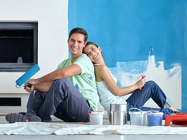 istock Couple sitting back to back with roller brushes in hand 626619616