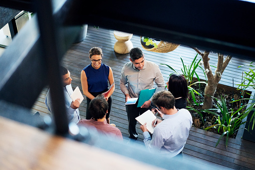 High angle view of business people discussing at lobby. Male and female professionals are working in office. Focus is on executives at workplace.