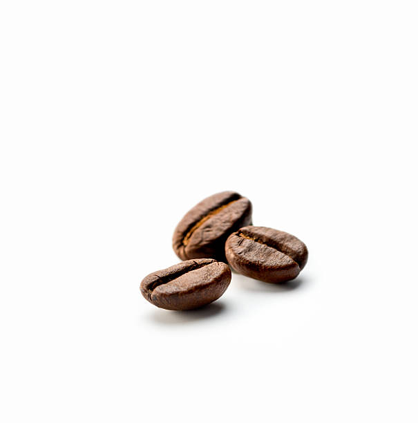 three Coffee Beans close-up of three Coffee beans on white background cooked selective focus indoors studio shot stock pictures, royalty-free photos & images