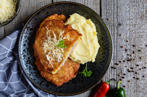 Fried pork cutlets coated in potato batter, studded with cheese and served with mashed potato