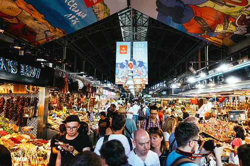 Barcelona, Spain - September 29, 2016: Tourists visiting the Boqueria Market, the most famous market in Barcelona. It is located in the heart of Barcelona on La Rambla street. The Boqueria Market offering wide selection of fruits, vegetables, spices, fish, meat etc.