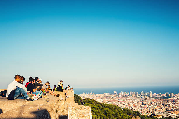 Barcelona, Spain - September 28, 2016: Tourists on Bunkers del Carmel (Búnquers del Carmel) enjoying the viewpoint in Barcelona. Group of young people are sitting on the wall watching Barcelona cityscape.