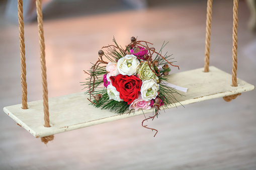 Wedding bouquet of artificial flowers on wooden swing. Marriage concept