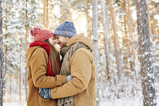 Young couple in winterwear embracing in park