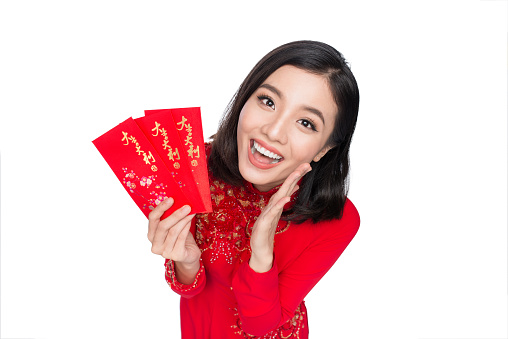 Portrait of a beautiful Asian woman on traditional festival costume Ao Dai holding red pocket - lucky money. Tet holiday. Lunar New Year.