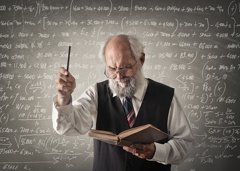 An old professor teaches mathematics front of the blackboard