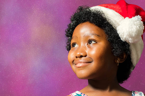 istock Black girl wearing christmas hat looking at corner. 626637238