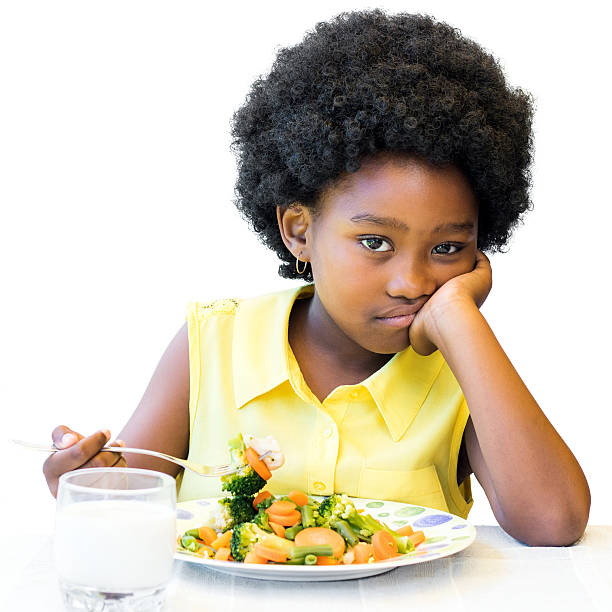 istock Bored looking african girl sitting with vegetable dish. 626639022