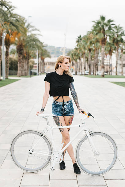 istock Beautiful Woman with Tattoos Standing behind a Bicycle 626642340