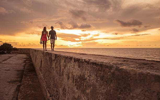 Tourists enjoying the sunset in Cartagena Tourists enjoying the beautiful sunset while walking on the wall at Cartagena - people traveling cartagena colombia stock pictures, royalty-free photos & images